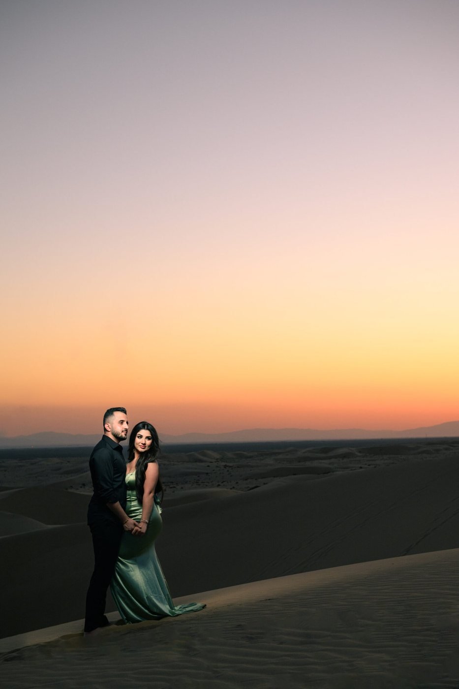 Couple on desert dunes at sunset